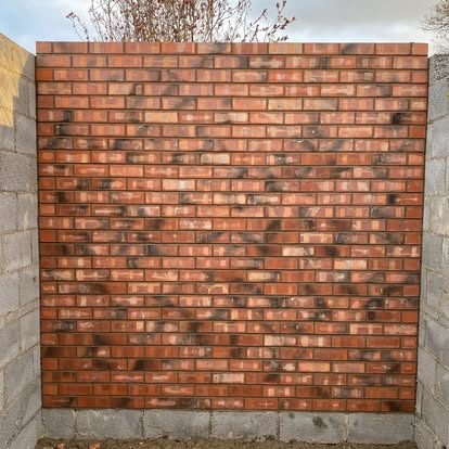 A flat panel of red brickwork with darker headers set in a pattern across it, finished with a coping course along the top